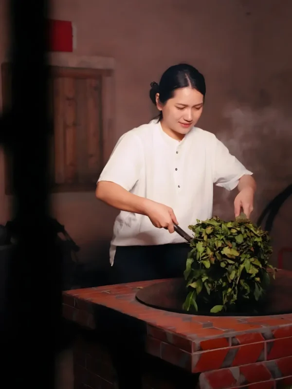 Tea artisan hand-panning Tieguanyin tea in a traditional wok, enhancing aroma, antioxidants, and cultural tea craftsmanship.