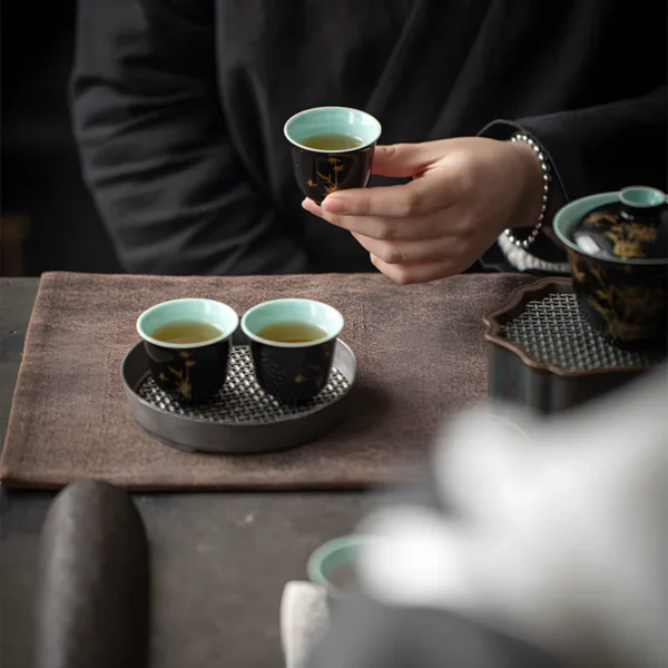 A person holding a cup from a polish ceramic tea set with painted details, part of a beautifully crafted ceramic tea set collection.