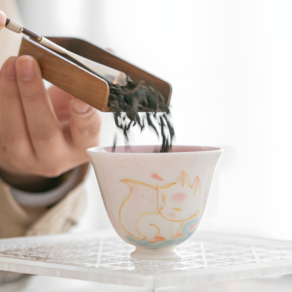 A hand holding a fox gaiwan set, part of a cute tea set and china porcelain tea set, ideal for traditional gongfu tea.