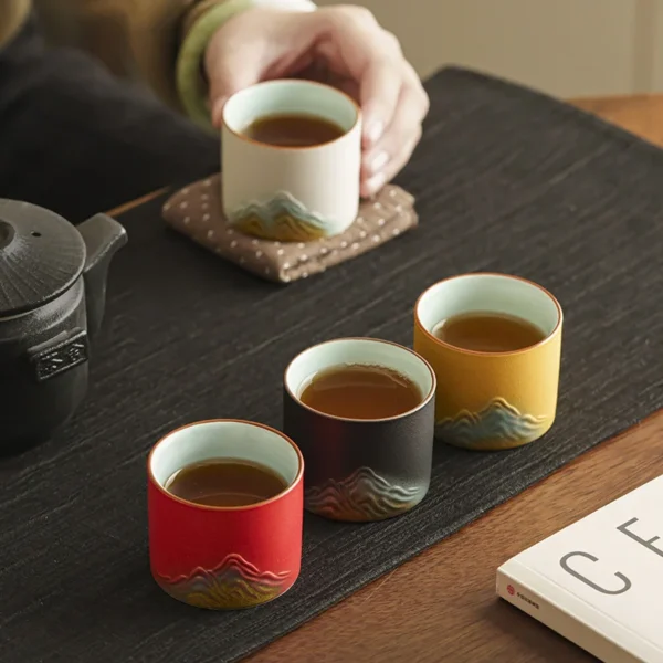 Elegant ceramic tea cups with mountain-inspired designs, vibrant exteriors, and soft blue interiors, ideal for tea enthusiasts.