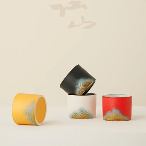 Handcrafted ceramic cups with mountain-inspired motifs, soft interiors, and vibrant colors, designed for tea lovers and collectors.