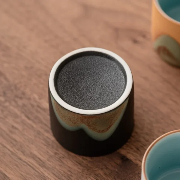 Close-up of an artisan ceramic cup featuring a textured base and mountain motif, designed for tea lovers and daily use.