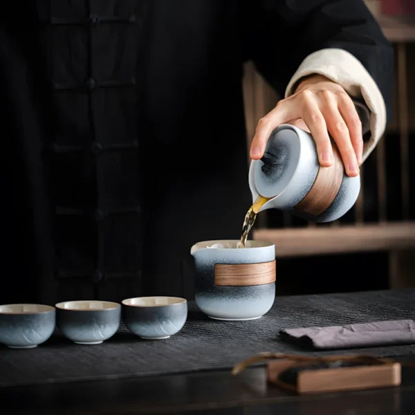 Elegant camping tea set, vintage tea service set with gradient tea cups and teapot, being used to pour tea during tea time.