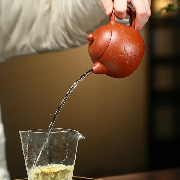 Effortlessly pour tea with the bamboo-engraved Yixing purple clay teapot, designed for smooth flow and enhanced tea brewing.