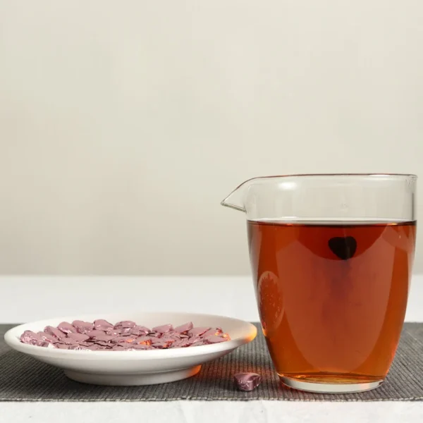 Glass pitcher of Rose Pu'er tea brewed from heart-shaped solid paste, accompanied by individually wrapped rose tea hearts.