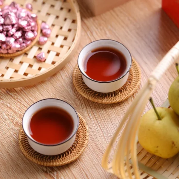 Two cups of brewed Rose Pu'er tea paired with heart-shaped tea pastes, highlighting its digestive benefits and social appeal.