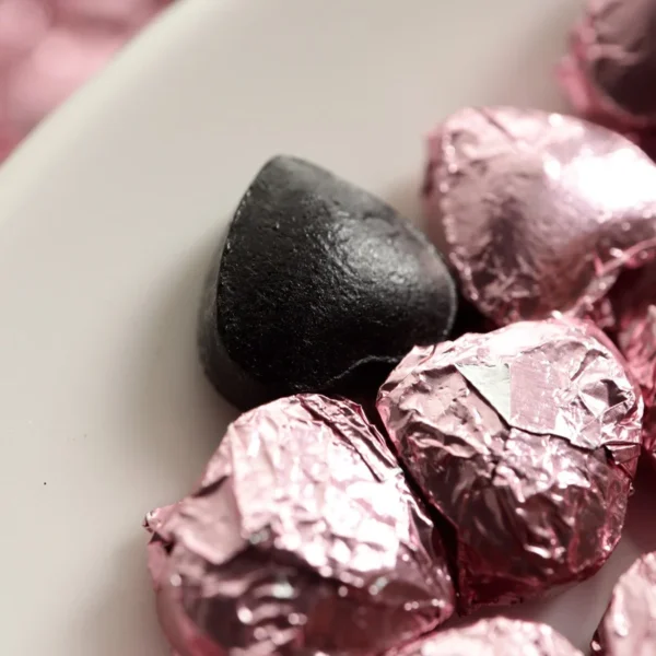 Close-up of heart-shaped Rose Pu'er tea paste, individually wrapped in pink foil, showcasing elegance, quality, and convenience.